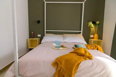 a bedroom with an orange wall and a bed at Curò in Cinisi