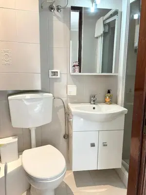 a white bathroom with a toilet and a sink at La Casa del Sole in Corleone