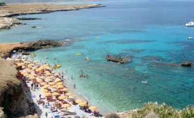 a beach with umbrellas and people in the water at L' arcobaleno in Castelluzzo