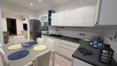 a kitchen with white cabinets and a table with chairs at Calandreafamily, appartamento 2 camere da letto vicino al centro Palermo in Palermo