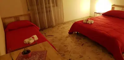a bedroom with two beds with red sheets and a window at Framamired in Palermo