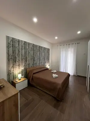 a bedroom with a bed and a large painting on the wall at Zabaria Home - Appartamenti tra Cefalù e Palermo in Casteldaccia