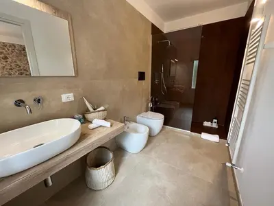 a bathroom with a sink and a toilet and a mirror at Curina Boutique Stay - Luxury Villa in the Sicilian Countryside in Castellammare del Golfo