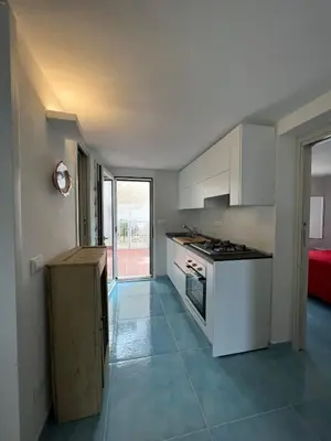 a kitchen with white cabinets and a stove top oven at Paradiso Isulidda in Macari