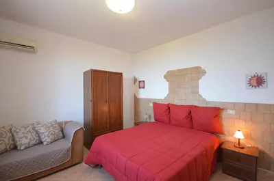 a bedroom with a red bed and a couch at Appartamenti da Clarissa in Macari