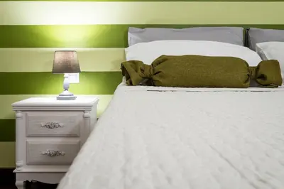 a bedroom with a white bed with a green wall at Quattro Canti Apartments in Palermo