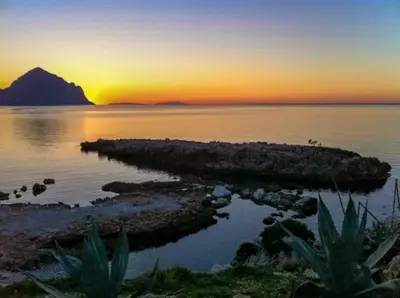 an island in the water with a sunset in the background at Baglio Fontana in Castelluzzo