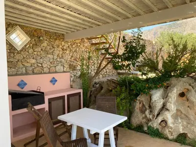 a table and chairs in front of a stone wall at Villetta Degli Oleandri in Castellammare del Golfo