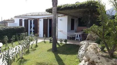 a white house with a hammock in a yard at Villetta Degli Oleandri in Castellammare del Golfo