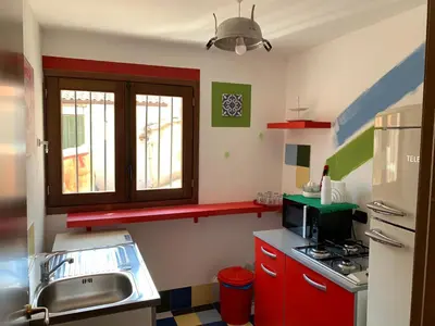 a small kitchen with red cabinets and a sink at Cialoma B&B in Palermo