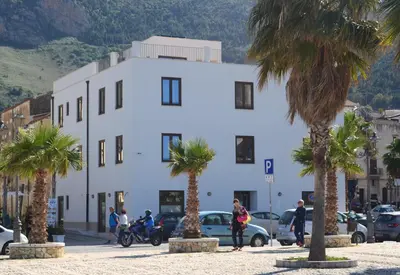 a white building with palm trees in front of it at Residence Itaca in Castellammare del Golfo