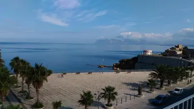 a view of a beach with palm trees and the ocean at Residence Itaca in Castellammare del Golfo