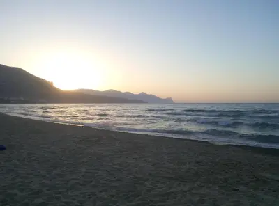 a beach with the sun setting over the ocean at Casa Vacanza Mare in Castellammare del Golfo