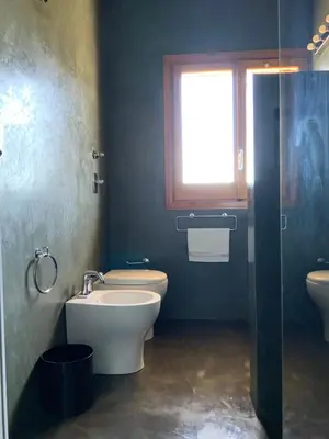 a bathroom with a toilet and a sink and a window at Villa Il Cappero in San Vito lo Capo