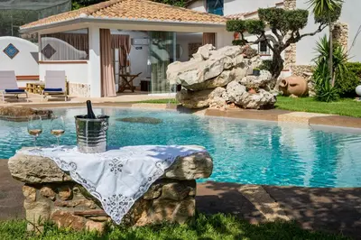 a table with wine glasses on it next to a swimming pool at Villa esclusiva Milazzo Annarita in Castellammare del Golfo