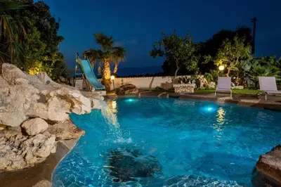 a swimming pool with a slide in a backyard at night at Villa esclusiva Milazzo Annarita in Castellammare del Golfo