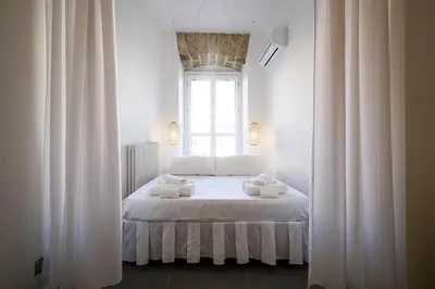 a bedroom with a bed with white sheets and a window at Cassari UpArtments in Palermo