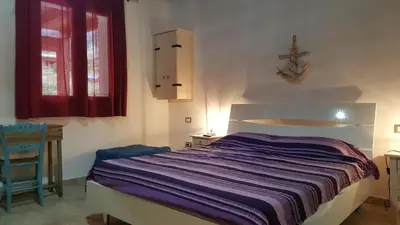 a bedroom with a bed and a chair and a window at Casolare La Torre in Scopello