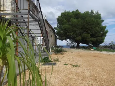 a staircase next to a building with a tree at Casolare La Torre in Scopello