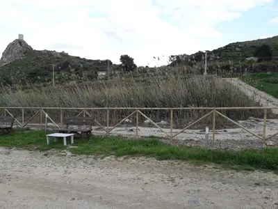 a fence next to a dirt road with a bench at Casolare La Torre in Scopello