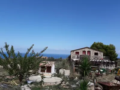 an old house with the ocean in the background at Casolare La Torre in Scopello