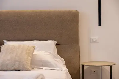 a bed with a large headboard and a side table at Le Muse Mondello in Mondello