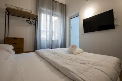 a bedroom with a large white bed with a flat screen tv at Vespri Apartments in Palermo