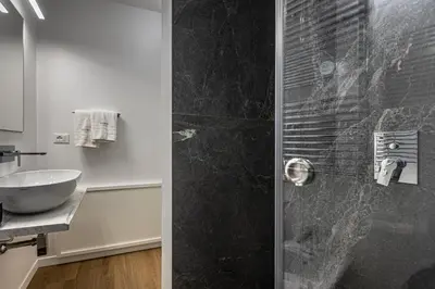 a bathroom with a glass shower with a sink at Vespri Apartments in Palermo