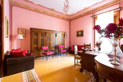 a living room with pink walls and a table and chairs at Casa nobiliare in Palermo