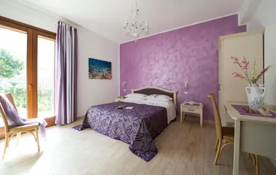 a purple bedroom with a bed and a table at I Segreti di Antonina in Castelluzzo