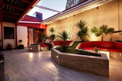 a man sitting in a courtyard with red couches and plants at Hospitality Hotel in Palermo