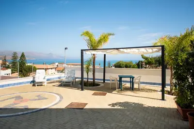 a patio with a table and chairs and the ocean at Villa Trinacria Apartments in Alcamo Marina