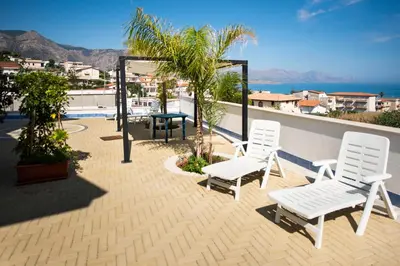 a patio with two white chairs and a table at Villa Trinacria Apartments in Alcamo Marina