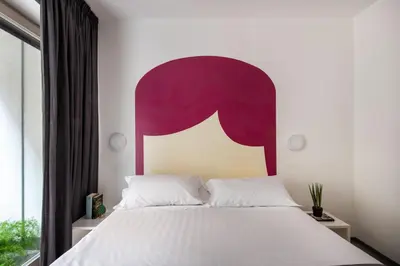 a bedroom with a white bed with a purple headboard at Pretoria Rooms in Palermo