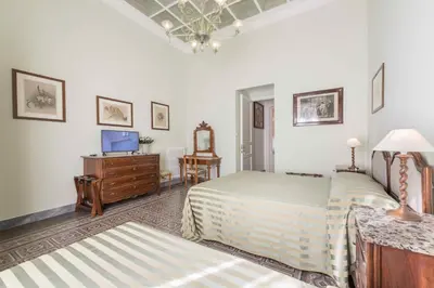 a bedroom with a bed and a desk and a television at Palazzo Benso in Palermo