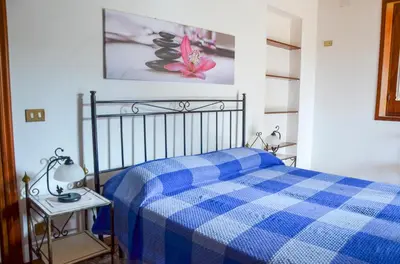 a blue checkered bed in a white room at La Grande Palma in Castelluzzo