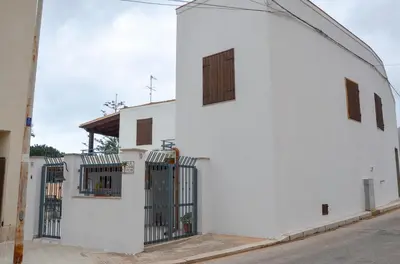 a white building with two windows and a fence at La Grande Palma in Castelluzzo