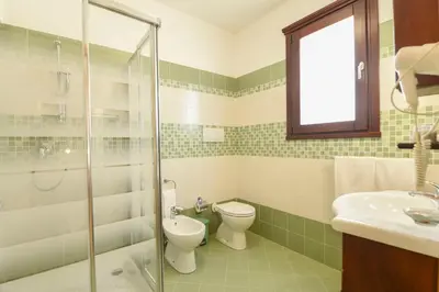 a bathroom with a toilet and a glass shower at Bed & Breakfast Goccia Marina in San Vito lo Capo