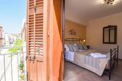 a bedroom with a bed and a balcony at Bed & Breakfast Goccia Marina in San Vito lo Capo