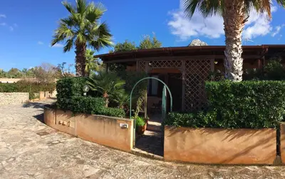 a house with a gate and palm trees in front of it at Acquamarina32 in San Vito lo Capo
