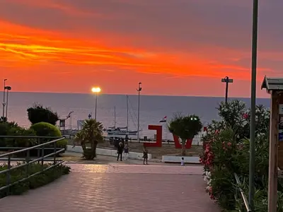 a sunset over the ocean with people walking down a sidewalk at Fiori d'Arancio in Terrasini