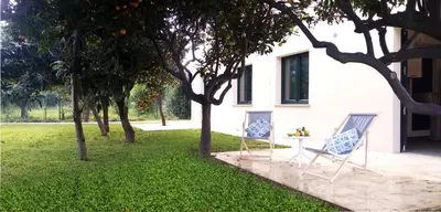 a house with two chairs and a table in the grass at Ville dell'Eden con 9 camere da letto in 6 unità abitative in Lascari