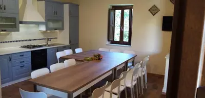 a kitchen with a wooden table and white chairs at Ville dell'Eden con 9 camere da letto in 6 unità abitative in Lascari