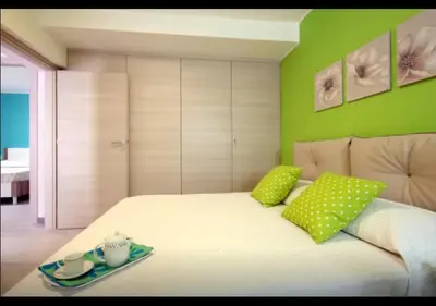 a bedroom with a white bed with green walls at Rainbow in Castellammare del Golfo