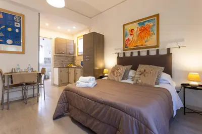 a bedroom with a large bed and a kitchen at Mondello House Eraclea in Mondello