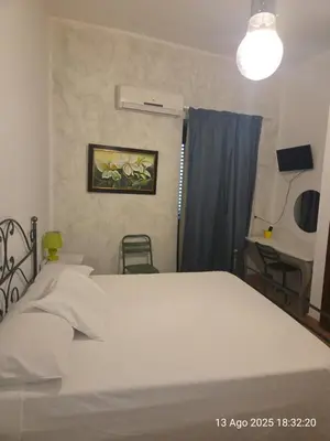a bedroom with a white bed and a window at Nostra casa rooms in Palermo