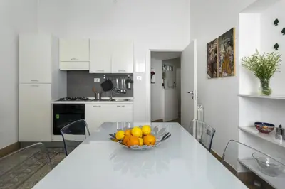 a white kitchen with a bowl of fruit on a table at Le case di Frelli in Palermo