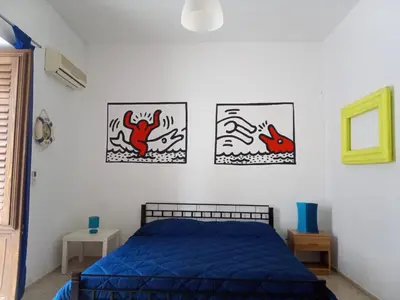a bedroom with a blue bed and three pictures on the wall at Appartamenti Blu Mare in Castellammare del Golfo