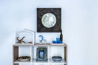 a shelf with a clock on a white wall at Lisca Bianca in San Vito lo Capo