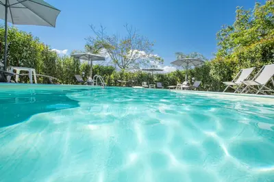 a swimming pool with chairs and an umbrella at Le Zagare in Lascari